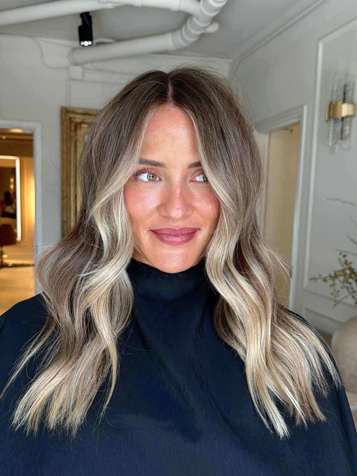 Woman with wavy brown hair and bright blonde highlights framing her face