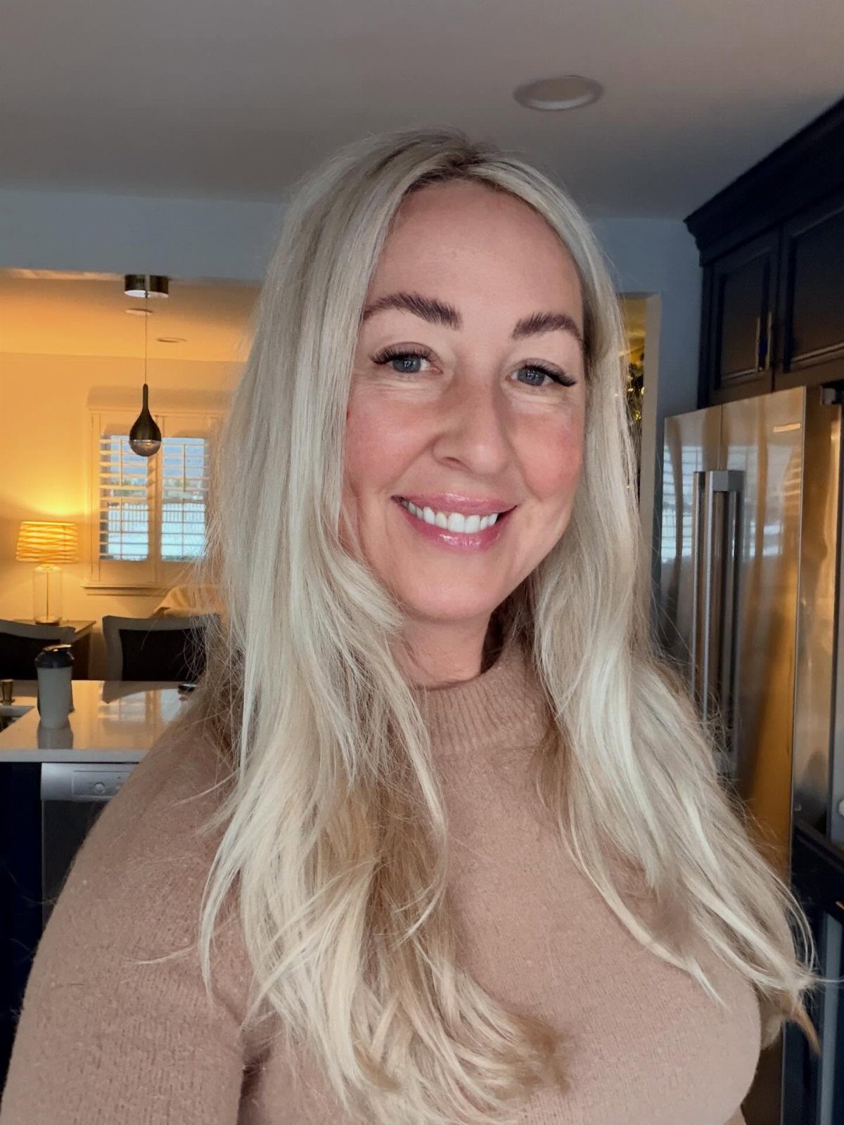 Woman with long, pale white-blonde hair smiling in a kitchen