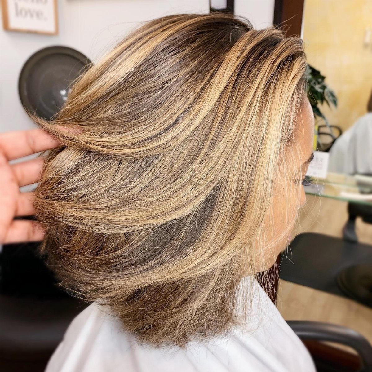 Layered brown hair with sweeping blonde balayage highlights in a salon