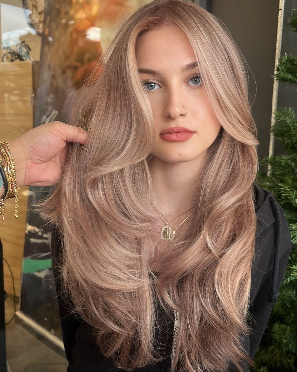 Woman with long beige-blonde hair as a hand lifts a section