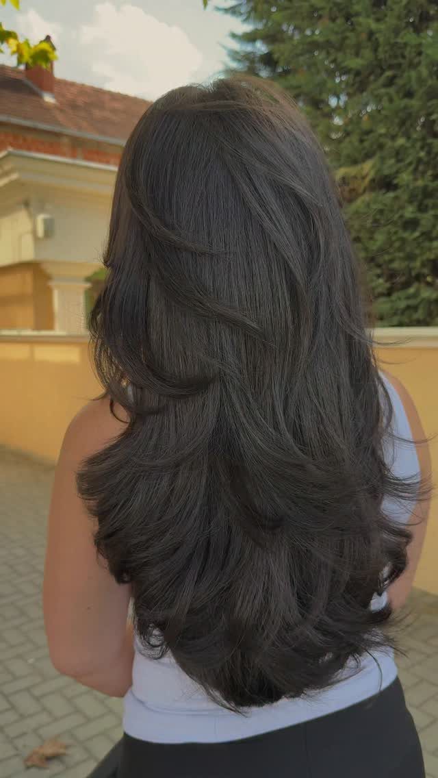 Long layered dark brown hair with curled ends seen from behind