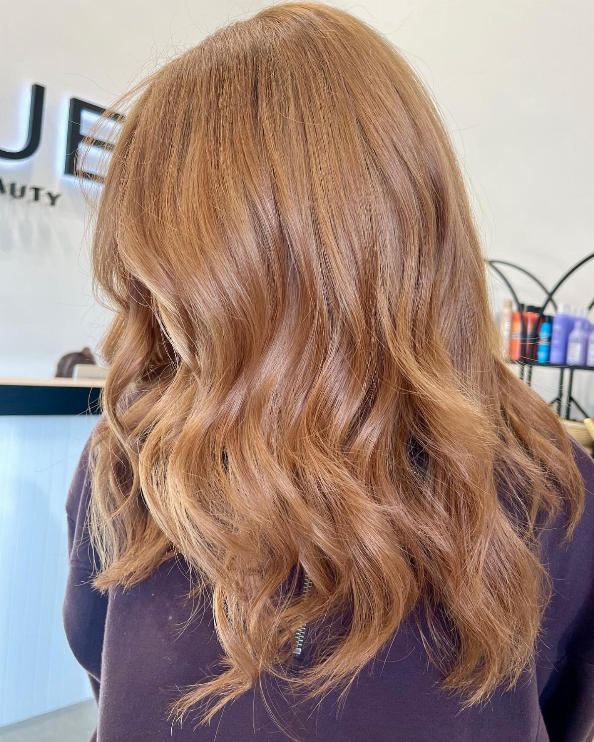 Long wavy golden brown hair with warm caramel tones in a salon