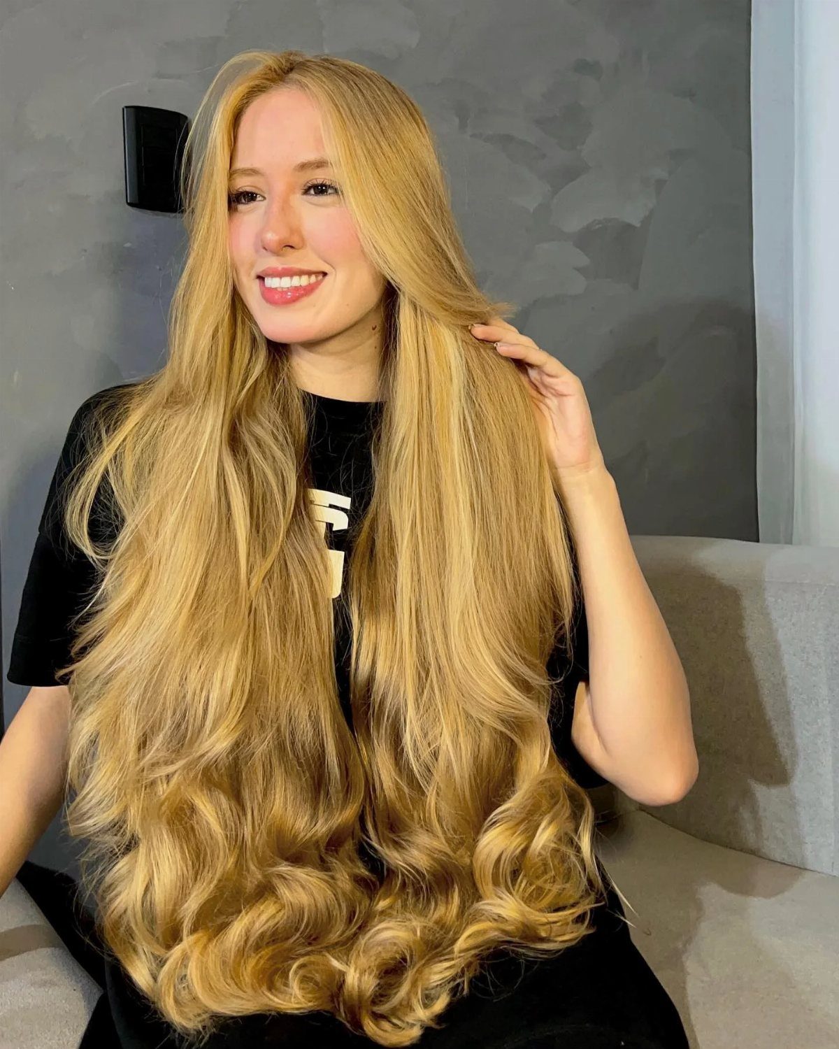 Woman showing long, wavy golden blonde hair in a salon
