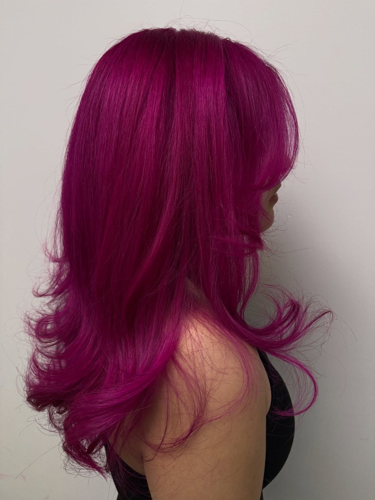 Long vivid magenta-pink hair with layered curls shown in profile
