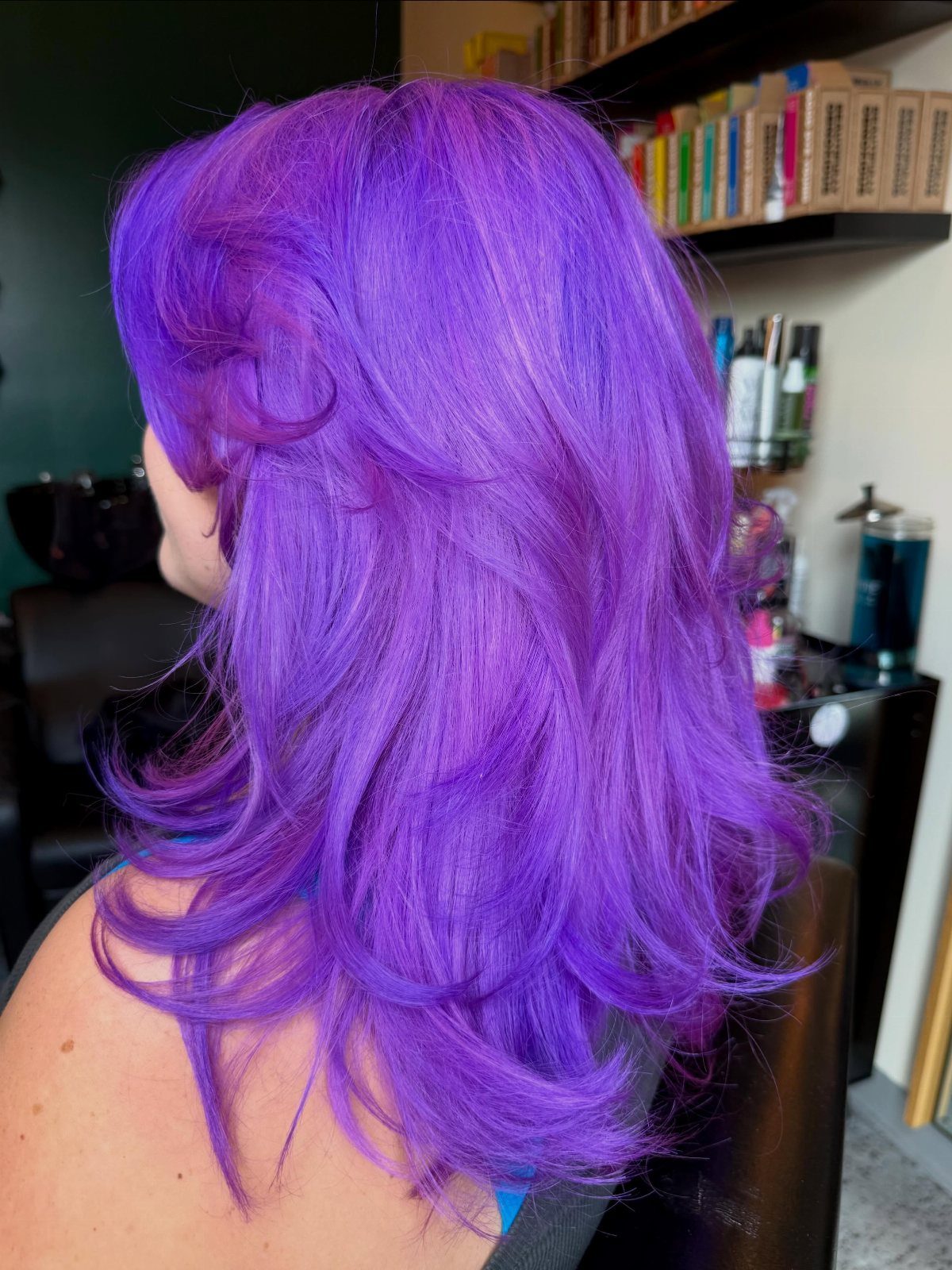 Long vivid purple hair styled in layered curls at a salon