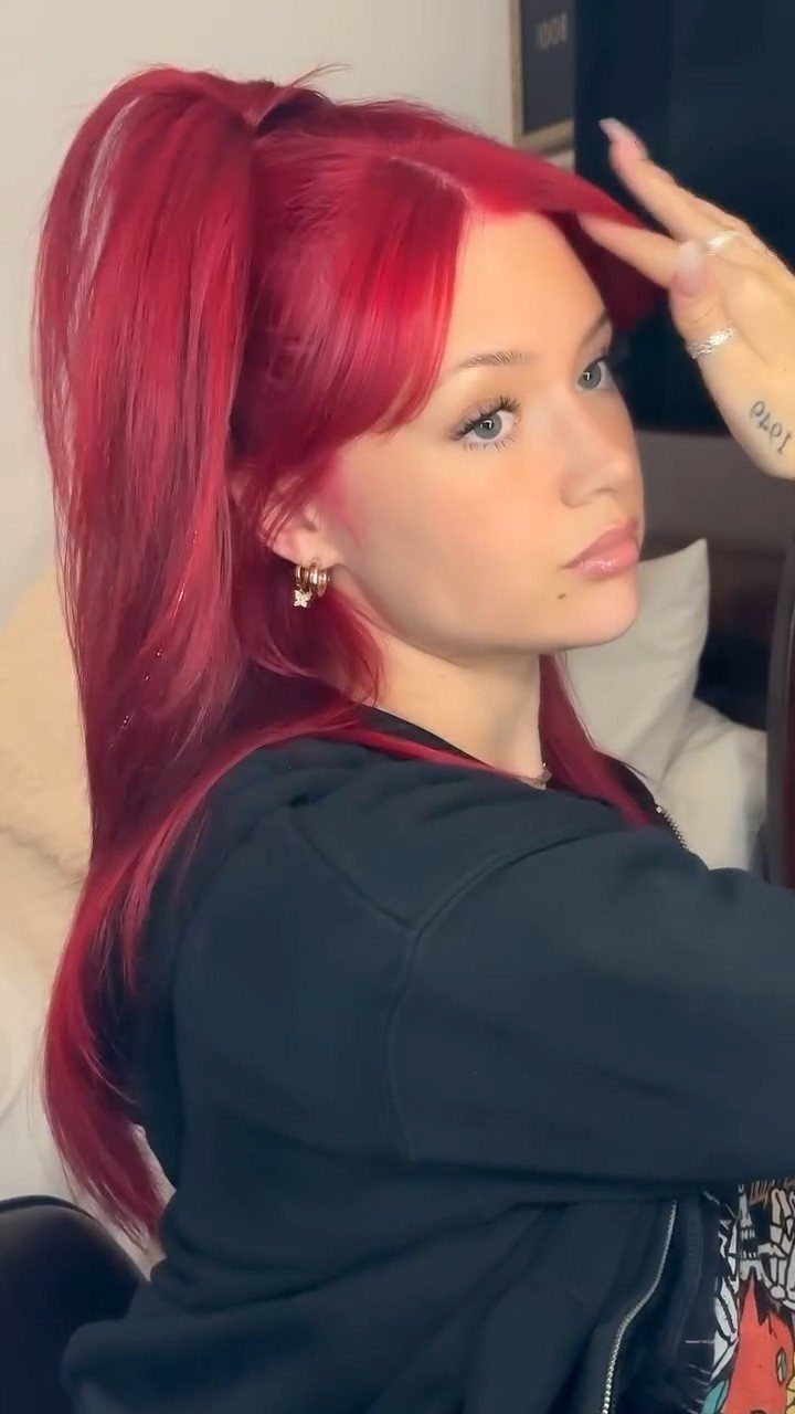 Woman displaying long, vivid red hair with a lifted side fringe