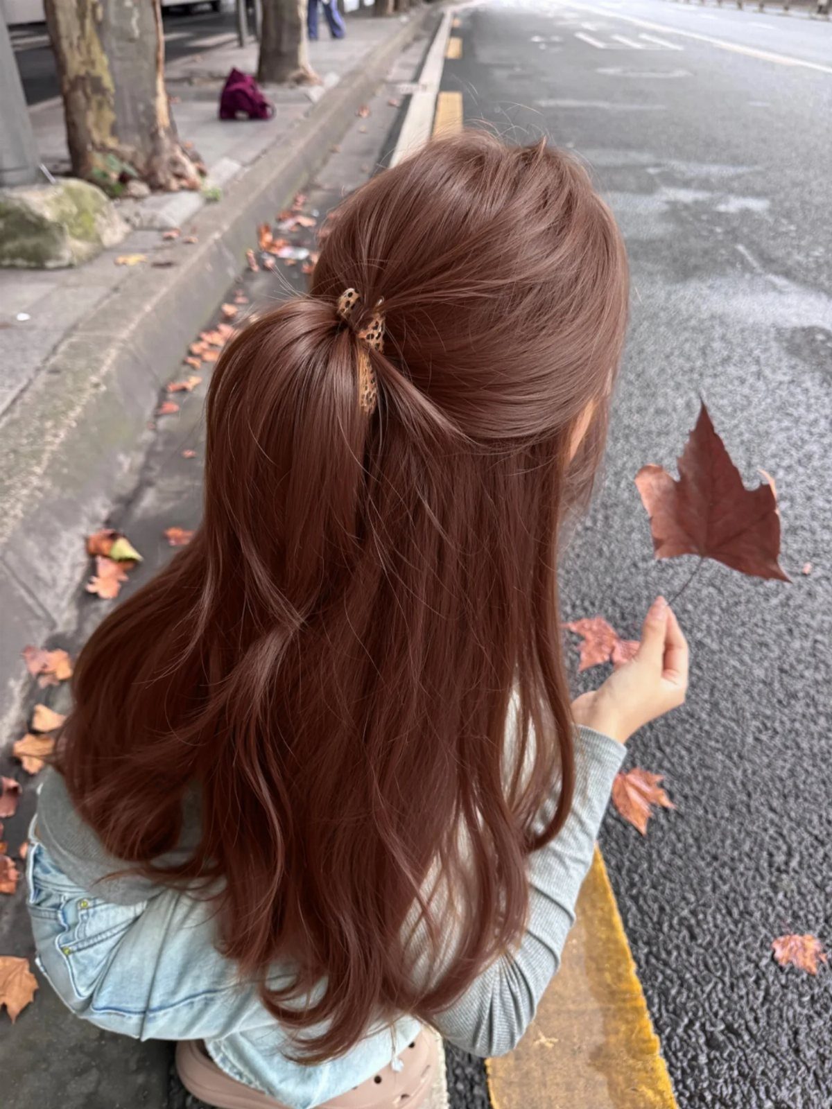 Long reddish-brown hair falls in loose waves, partly held with a gold clip