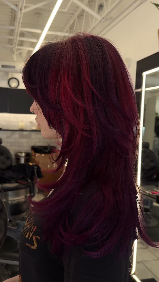 Layered burgundy-purple hair styled in a salon