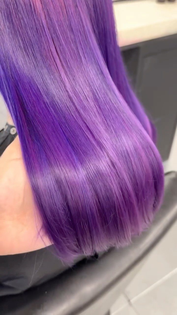 Glossy straight purple hair shown close up in a salon setting