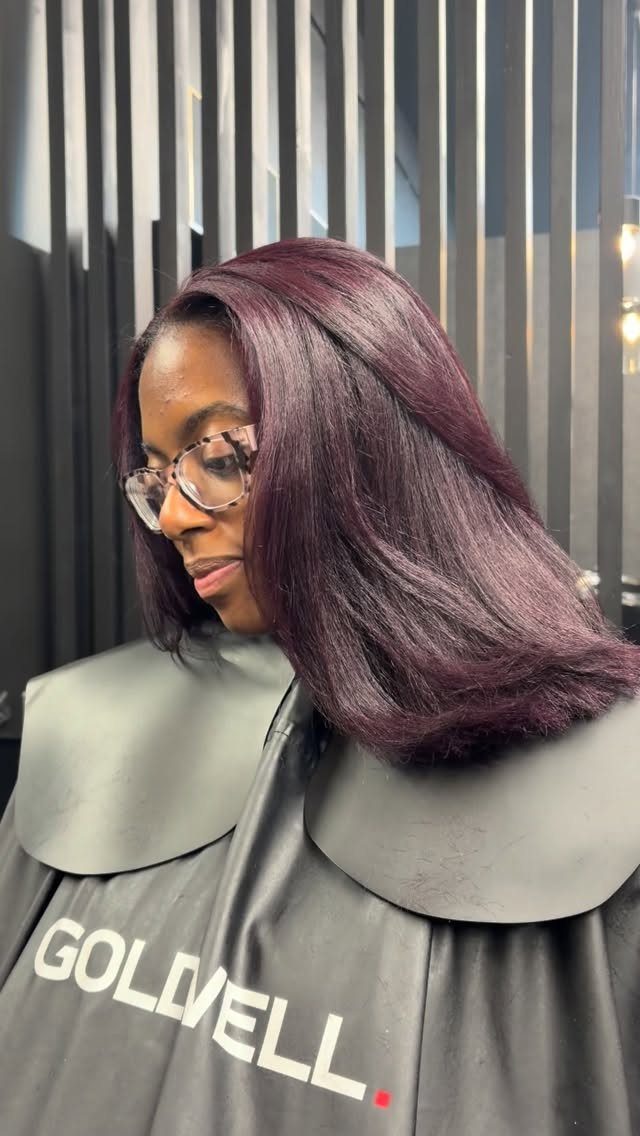 Woman displaying smooth plum-purple hair in a salon chair