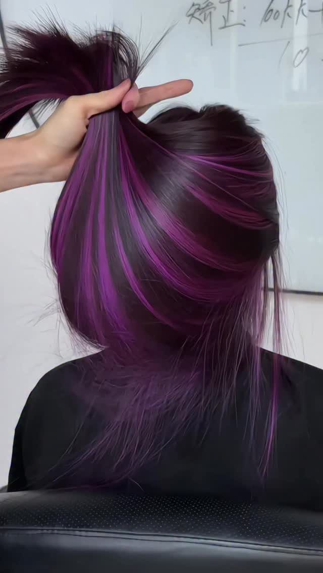 Dark purple hair with vivid magenta highlights revealed as a hand lifts a section