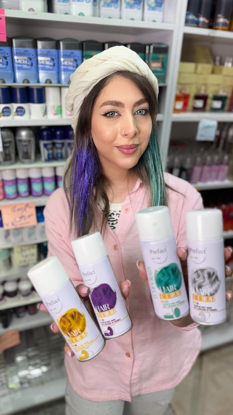 Woman with purple and teal hair holding bottles in a cosmetics shop
