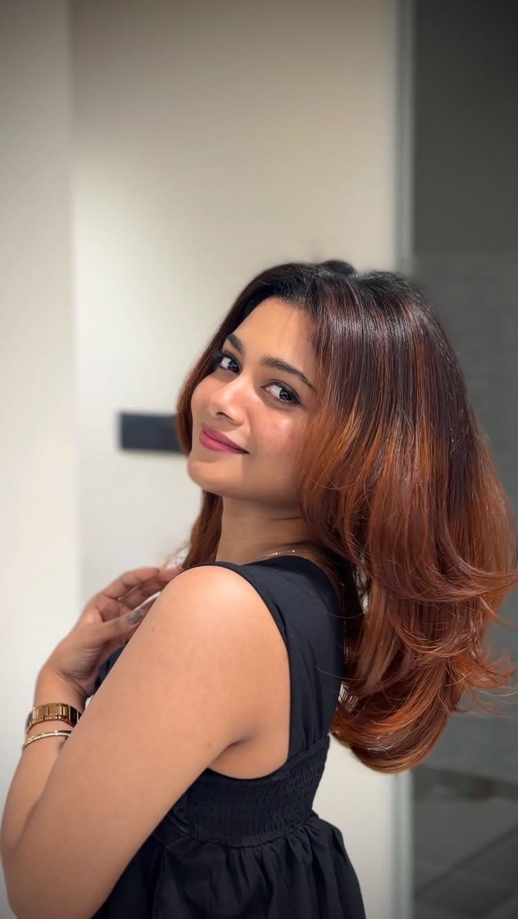 Woman showing long dark brown hair with warm copper highlights