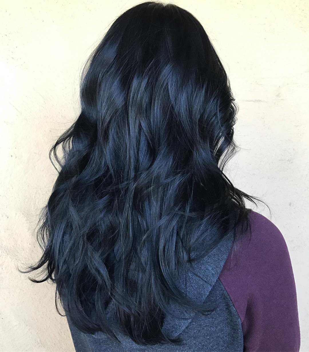 Glossy black wavy hair cascades over a gray and purple top