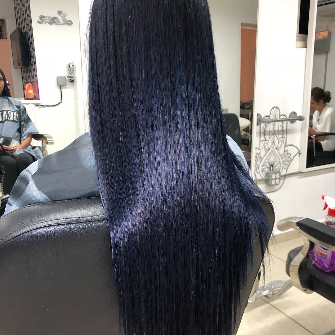 Long near-black hair shows a subtle midnight blue sheen in a salon