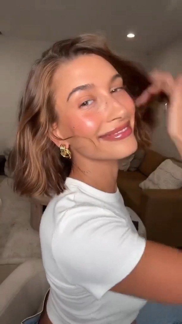 Woman showing shoulder-length warm chestnut brown hair with coppery highlights