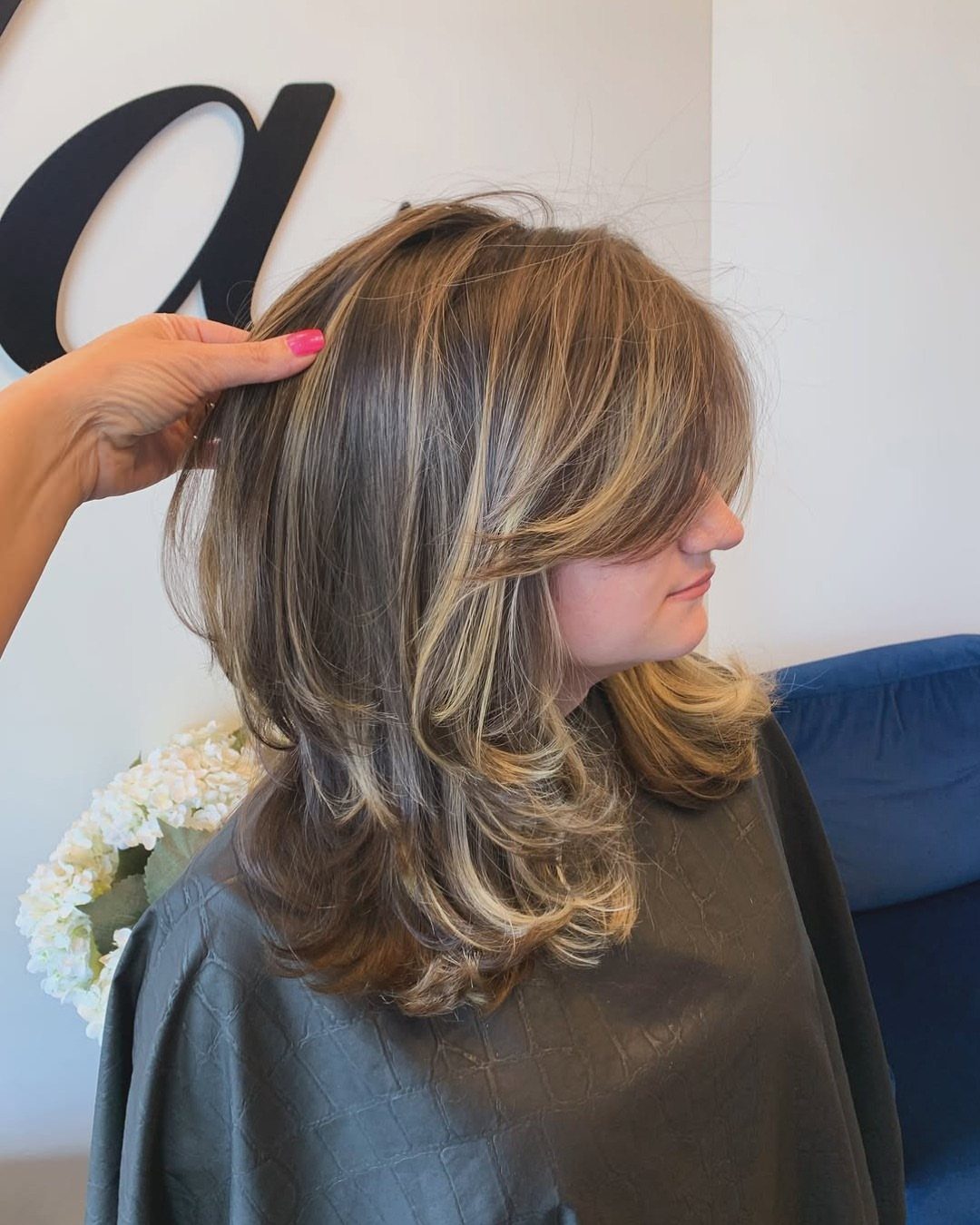 Layered highlighted hair styled in a voluminous, bouncy blow-dry