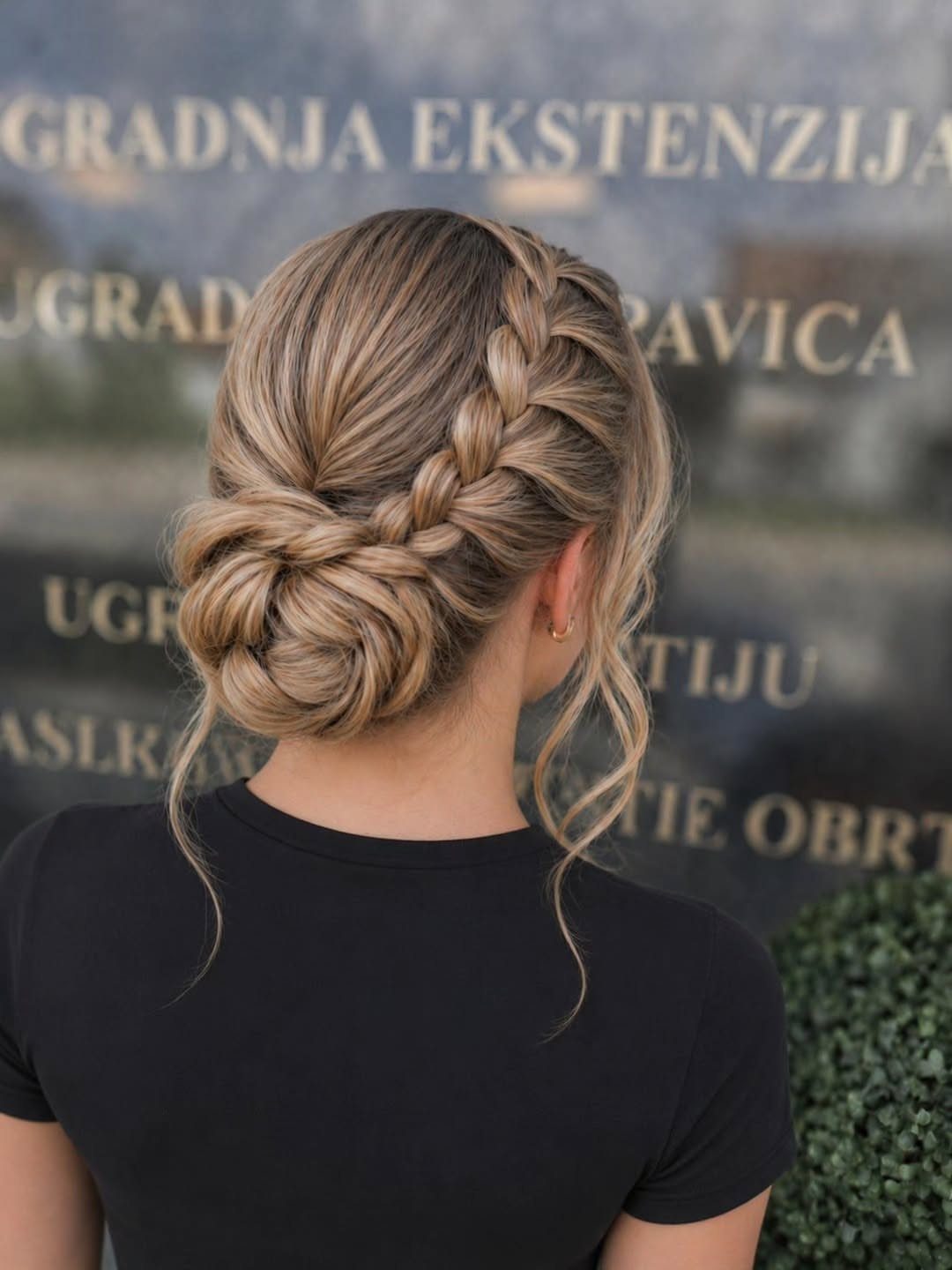 Braided blonde bun with loose curled strands viewed from behind
