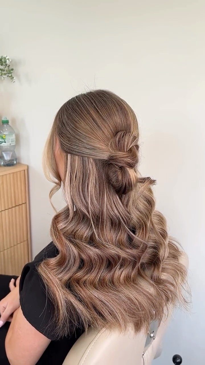 Twisted half-up hairstyle pins back the front sections over long, loose brown waves