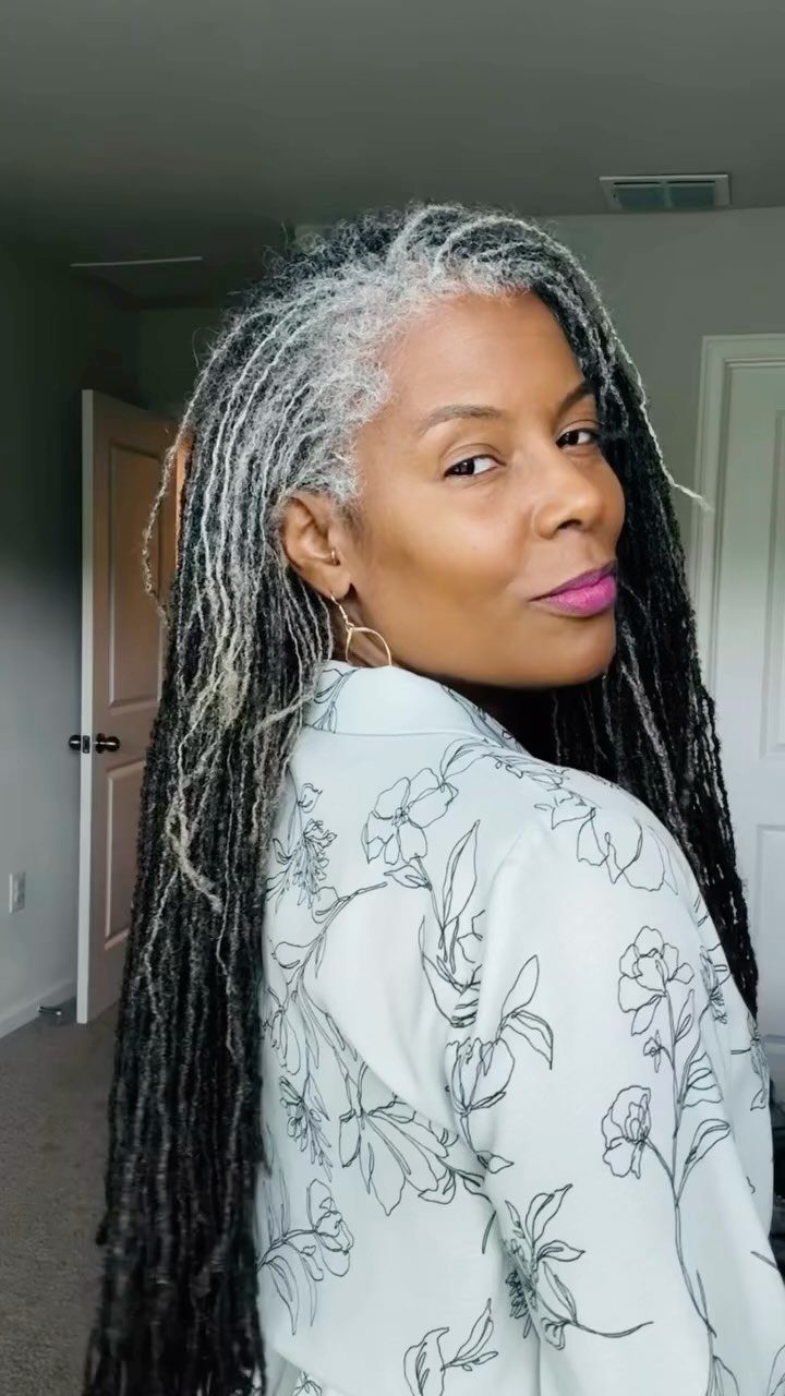Woman with long black and natural gray locs looks over her shoulder