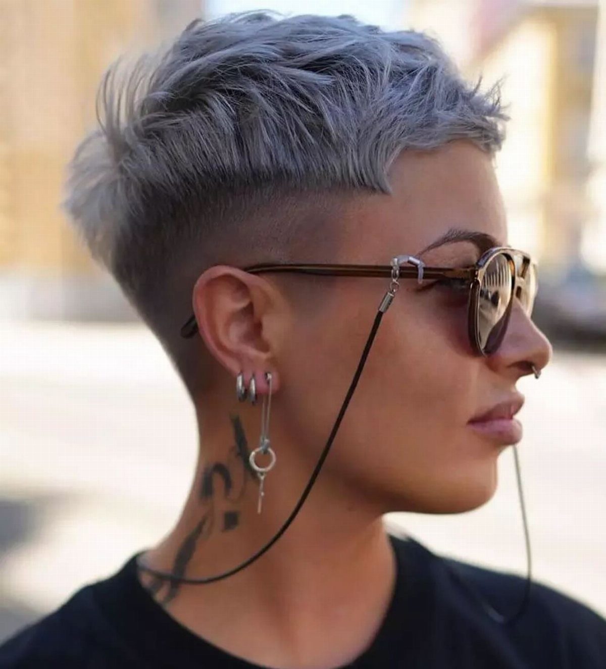 Short silver-gray hair with shaved sides and a textured, swept-up crown