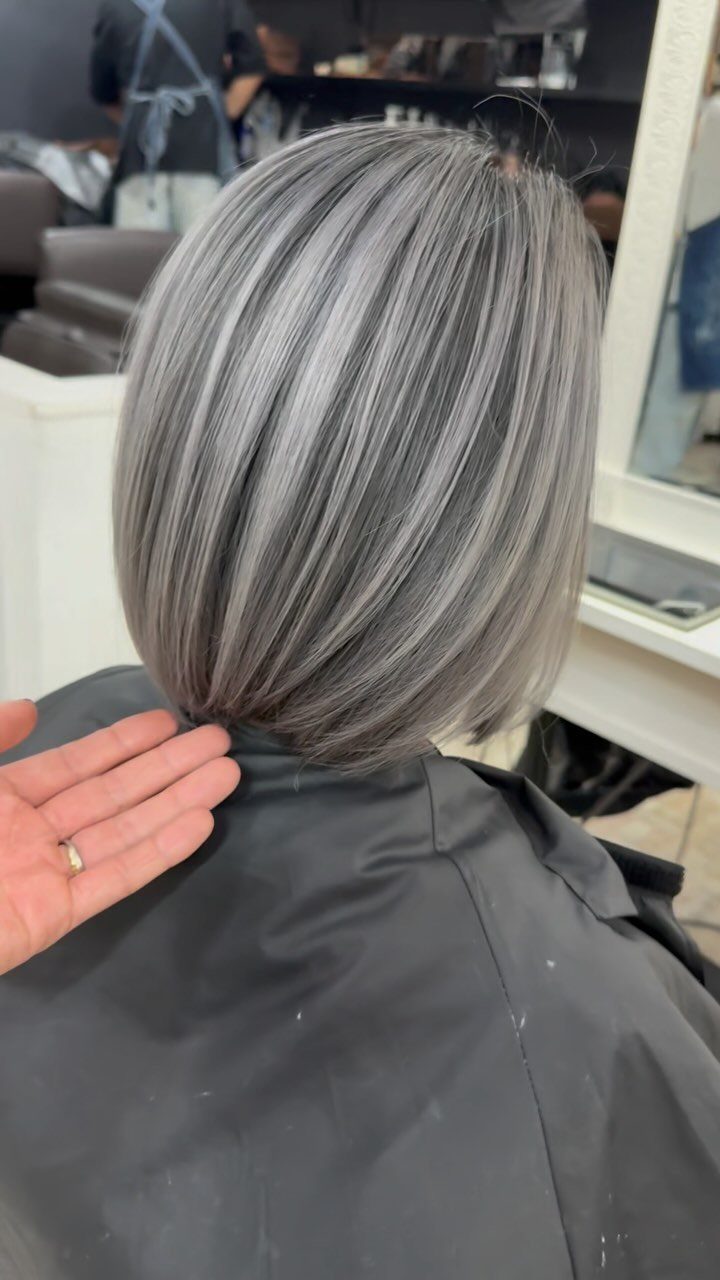 Short silver-gray bob with darker lowlights, shown from behind in a salon