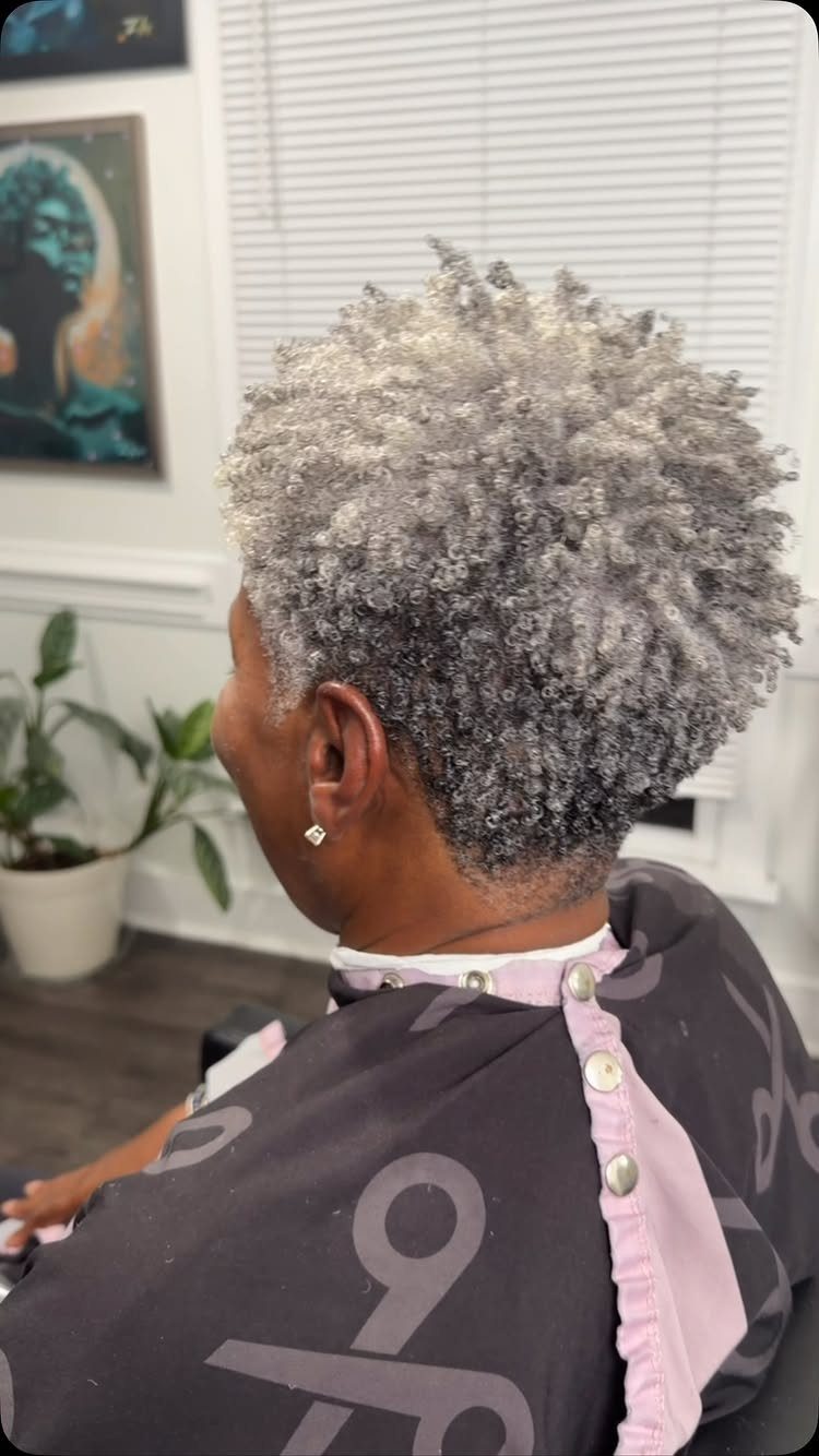 Short silver-gray curls on a seated salon client beneath window blinds