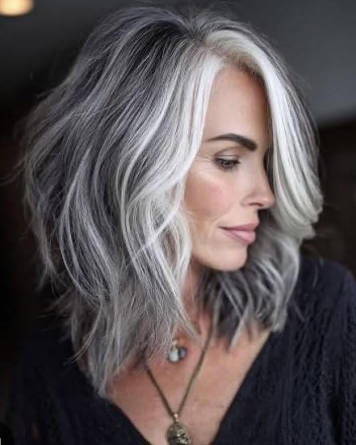 Woman with voluminous, shiny gray hair styled in soft shoulder-length waves