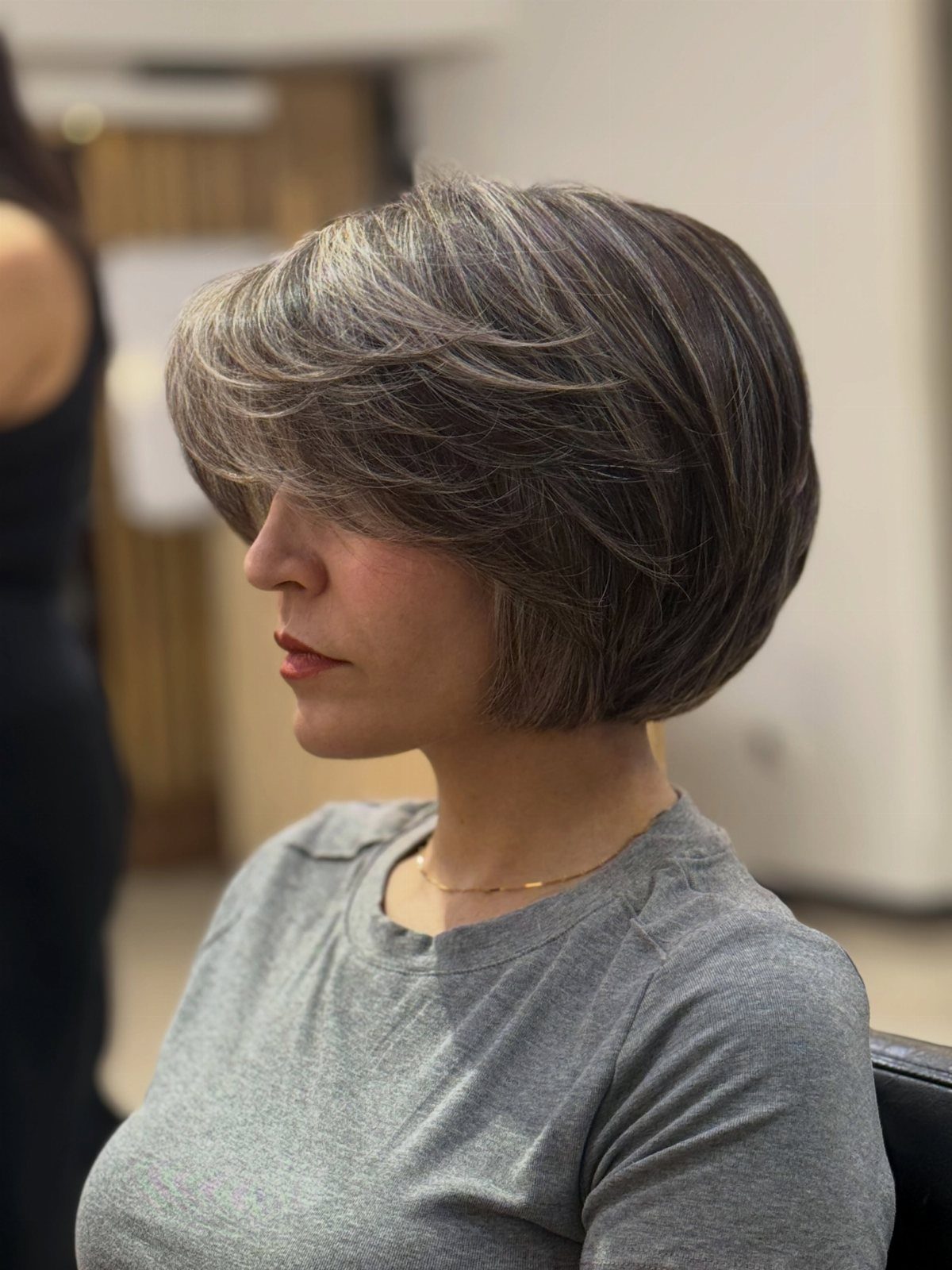 Woman with a rounded gray bob and voluminous, layered sides at a salon