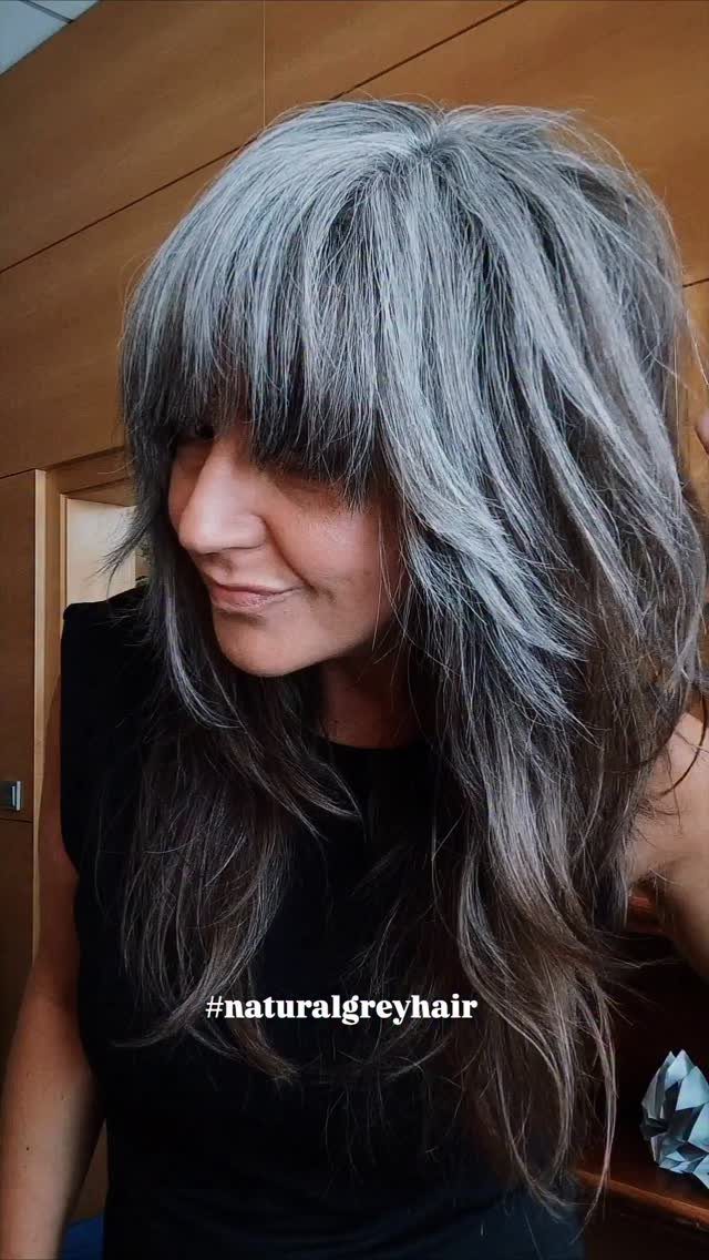 Woman with long silver-gray waves and a textured, full fringe