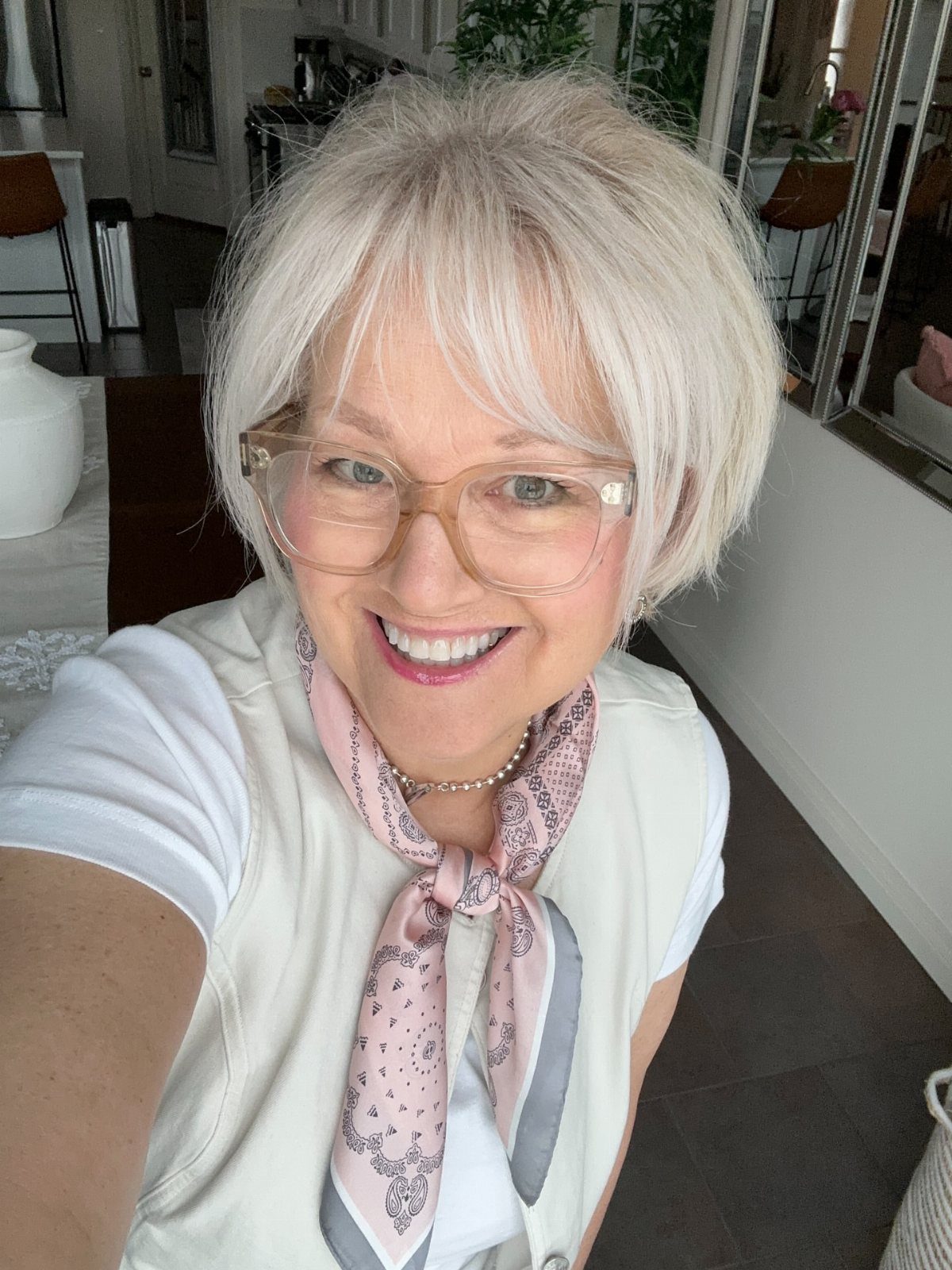 Older woman with a short white bob haircut, wispy bangs, and clear glasses