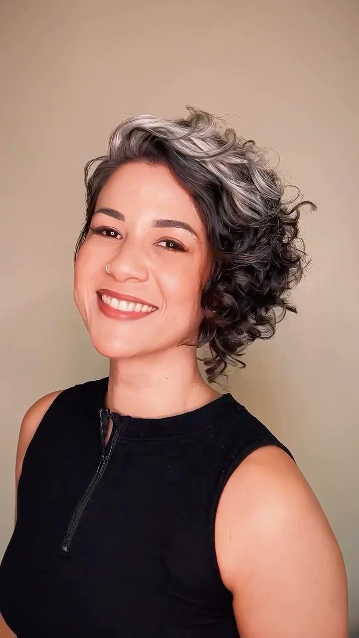 Woman showing a short, layered silver-gray curly haircut