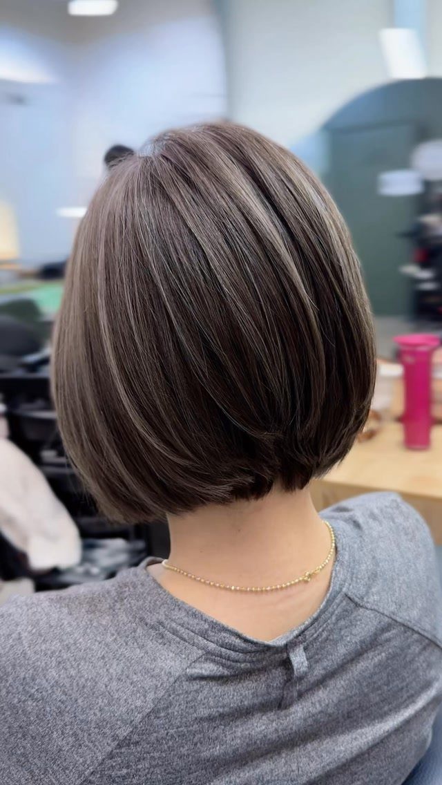 Rounded gray-brown graduated bob layered shorter at the nape in a salon