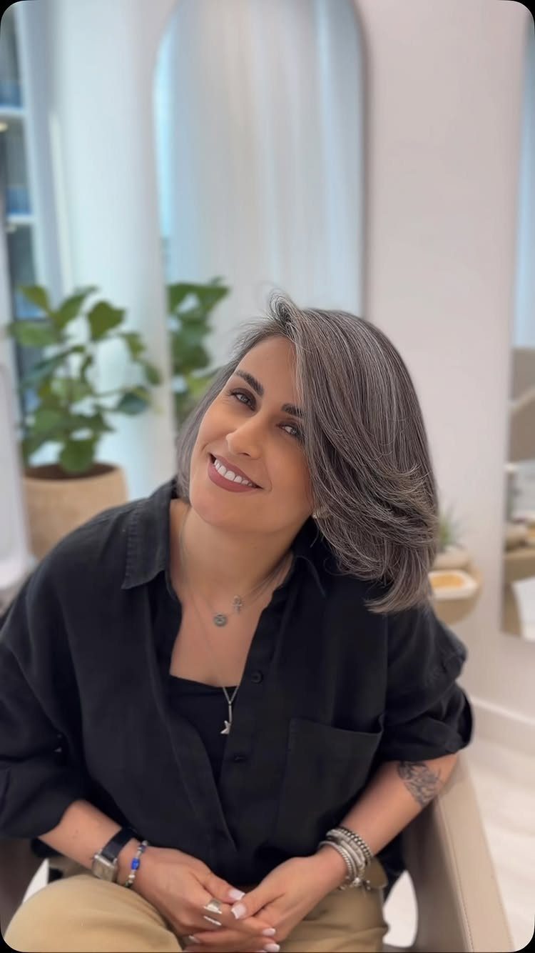 Woman with a blended gray-brown bob seated in a bright salon