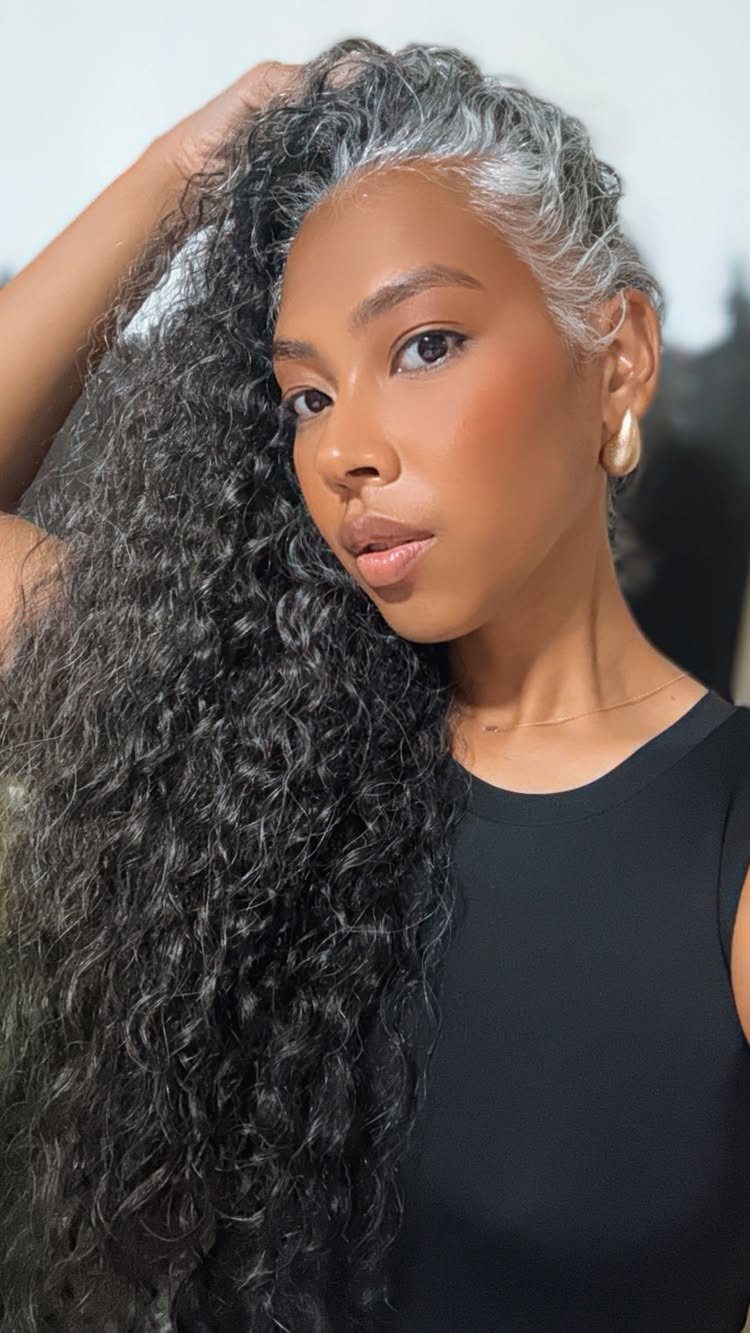 Woman posing with long dark curls and prominent gray roots
