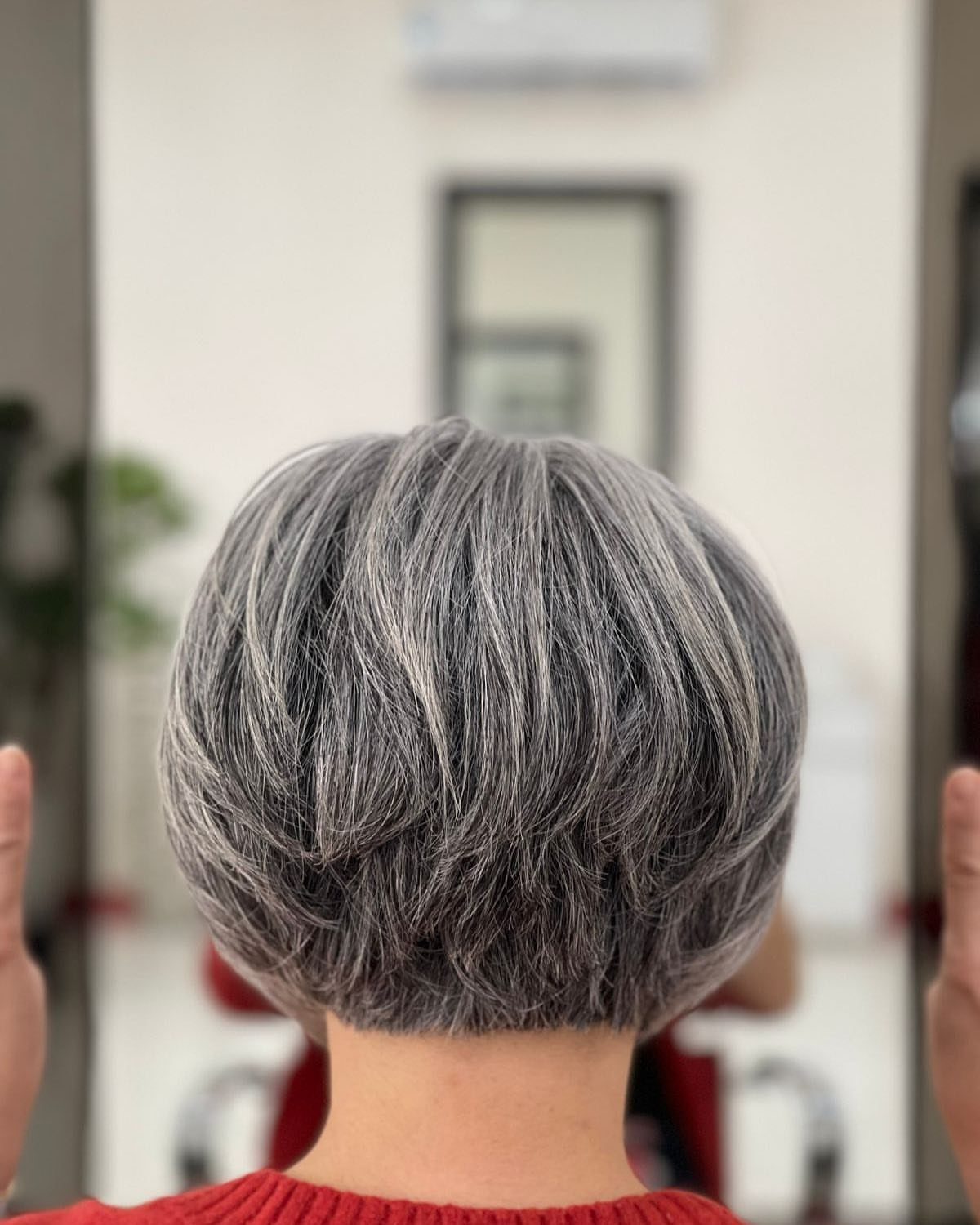 Short layered gray hair with a rounded, feathered shape viewed from behind