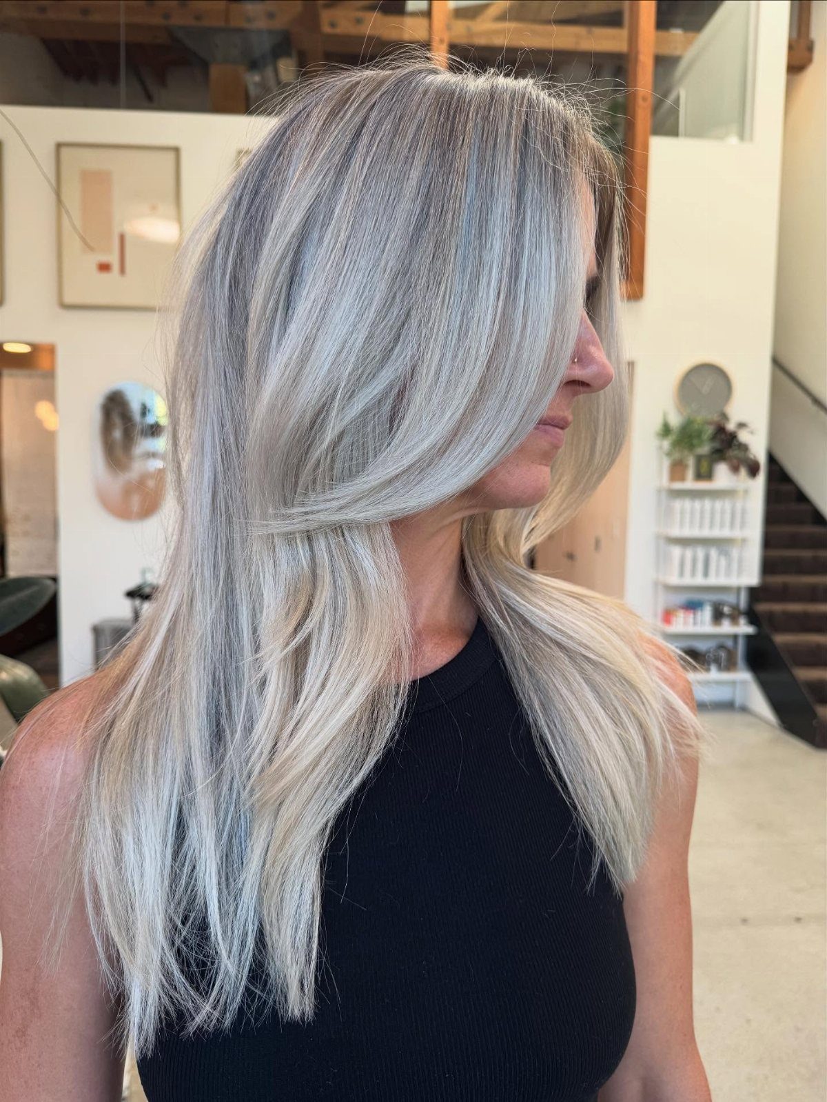 Long platinum-gray hair falls past a woman's shoulders in a salon