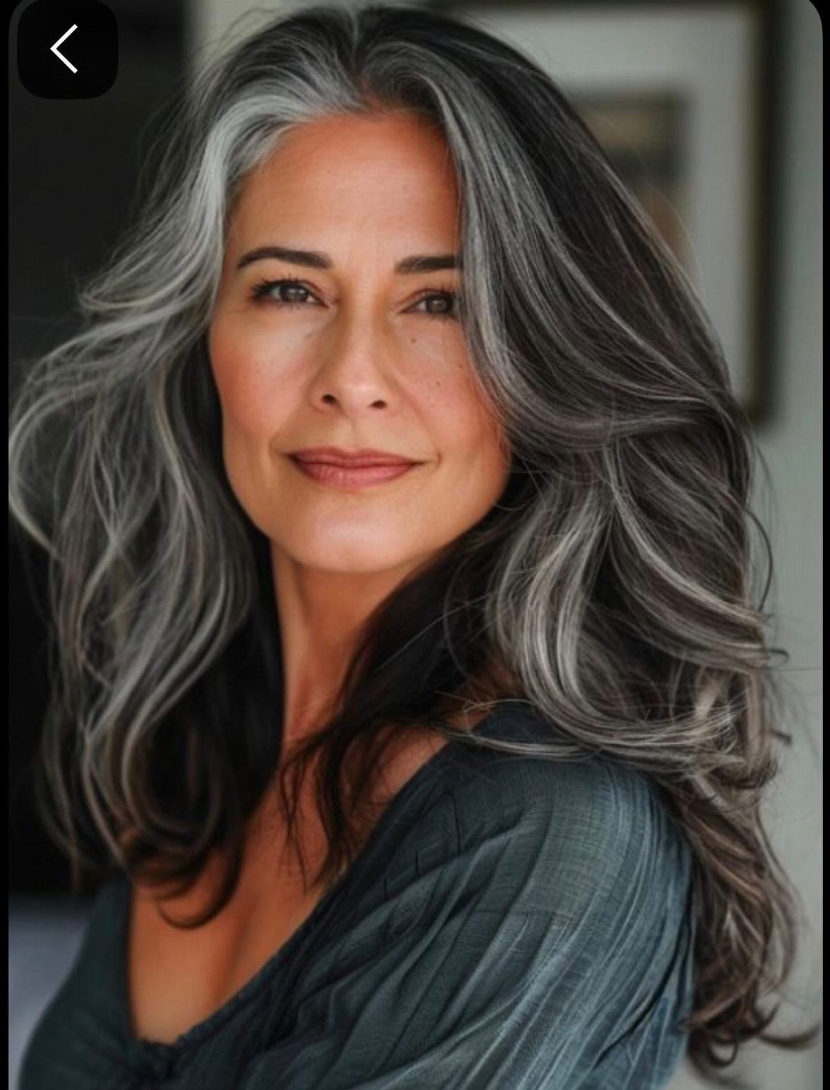 Woman with long wavy salt-and-pepper hair and silver strands