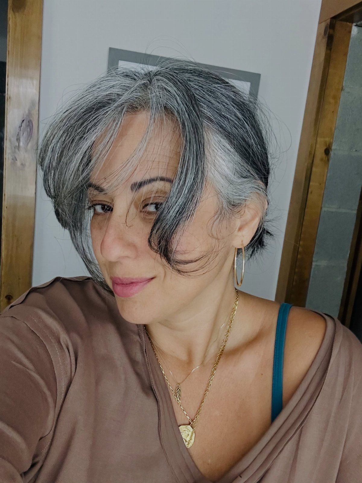 Woman with layered gray hair and side-swept bangs posing indoors