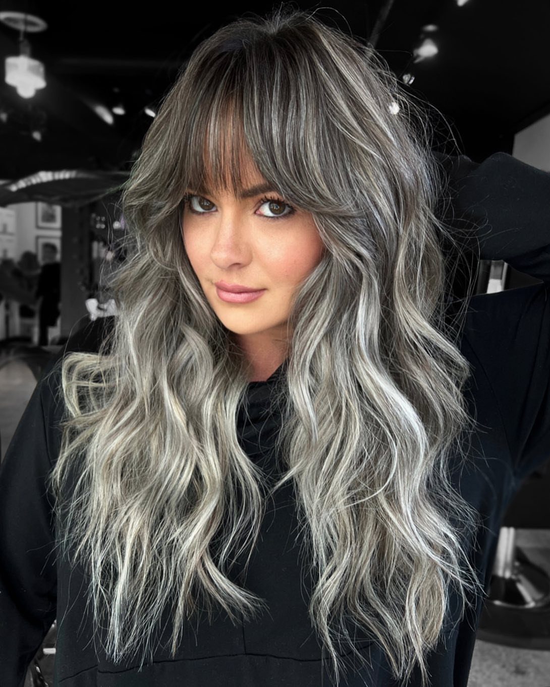Woman with long wavy gray hair and blended silver strands in a salon