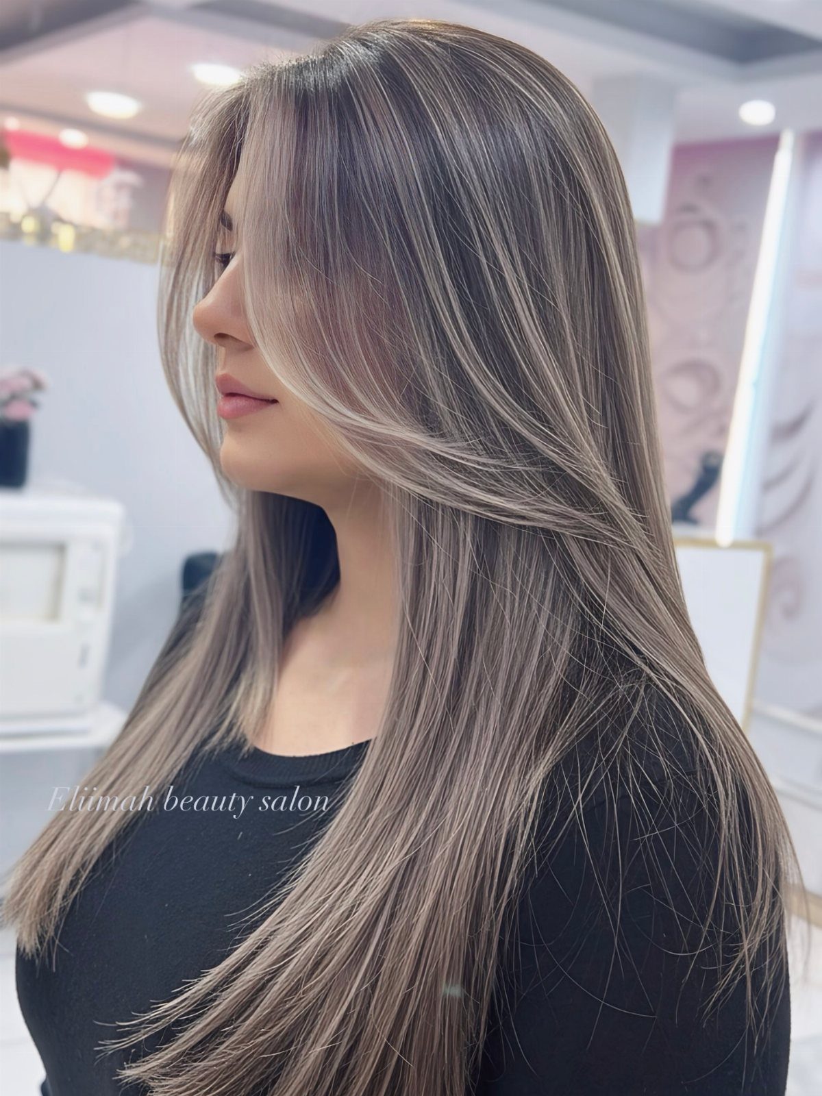 Woman with long ash-brown hair and fine blonde babylights in a salon