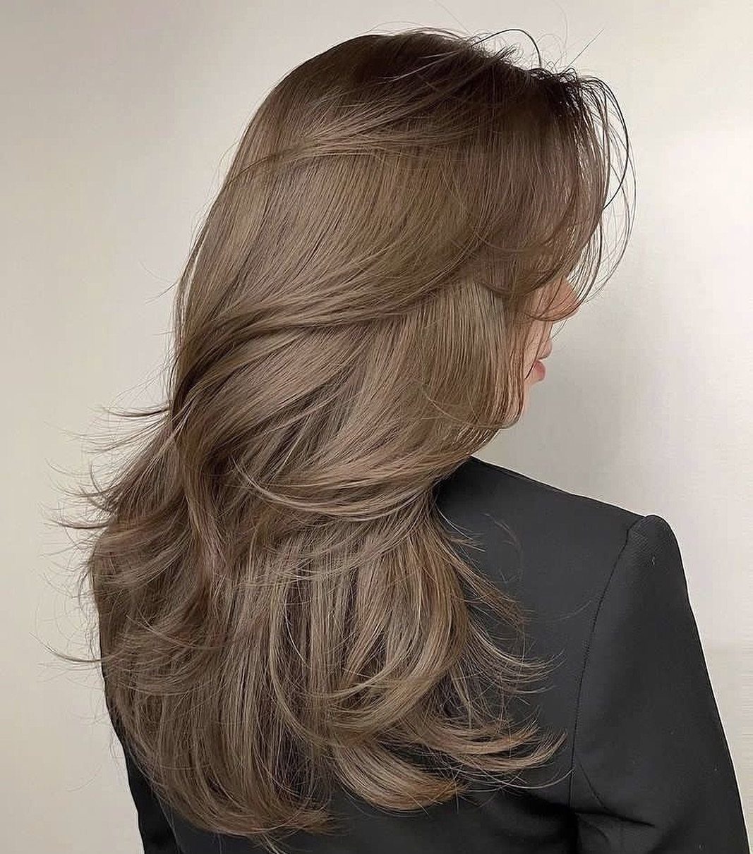 Long layered dark blonde hair with cool ash tones shown from behind