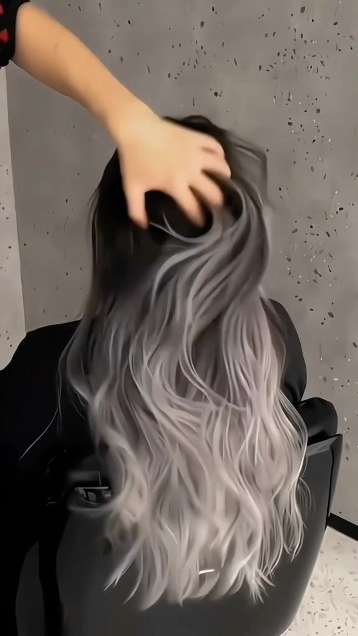 Long wavy hair fades from dark roots to silvery gray ends