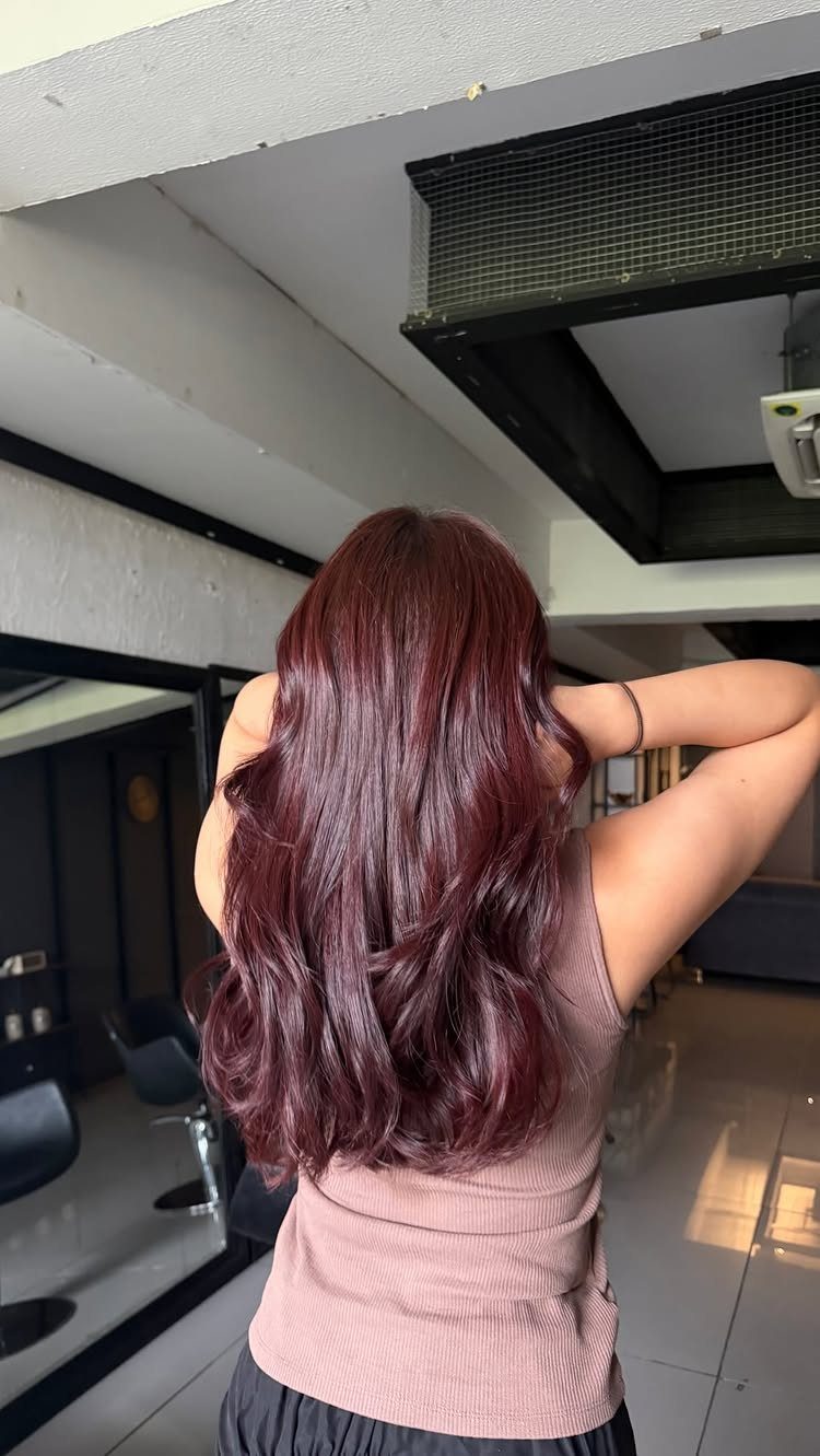 Long wavy red-brown hair shown from behind in a bright salon