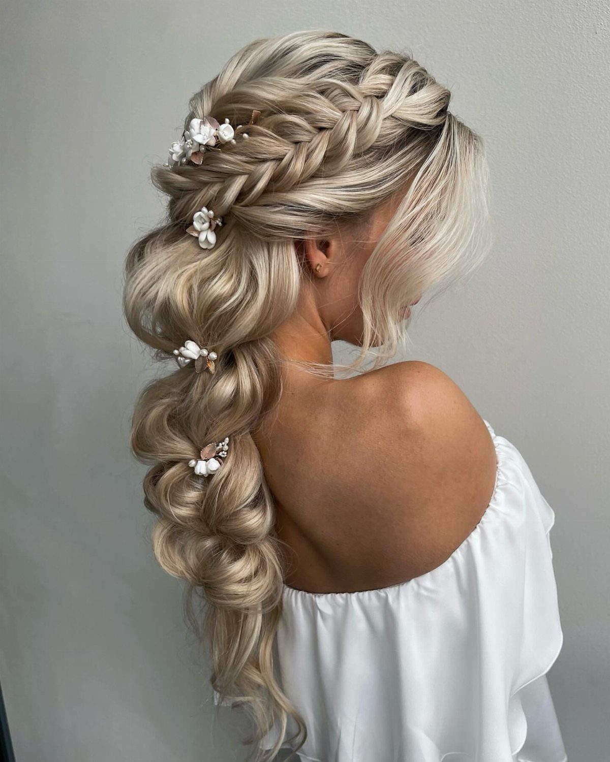 Long blonde hair styled in an embellished braid with cascading curls
