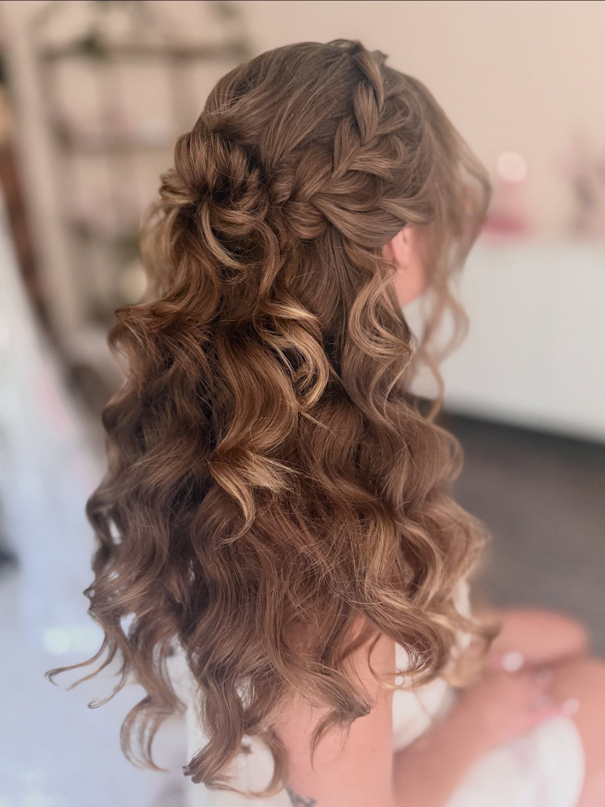 Long brown hair styled half-up with braids and voluminous cascading curls