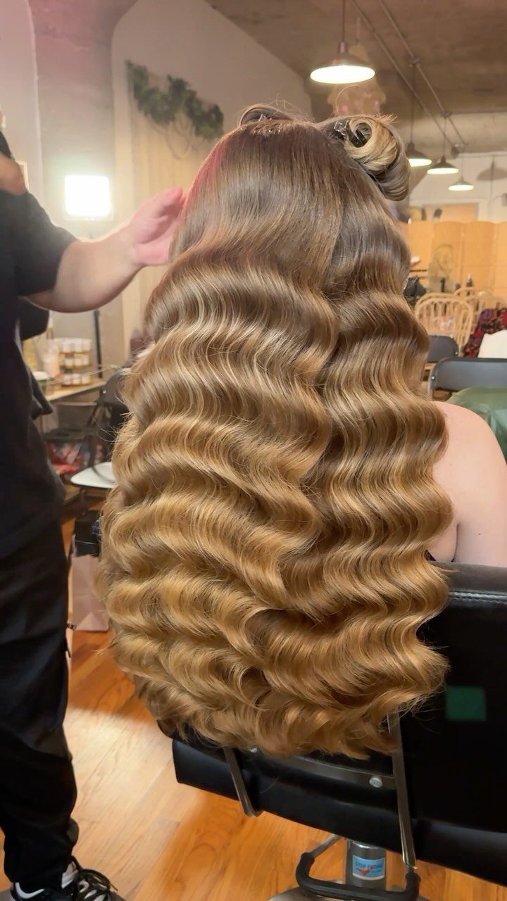 Long blonde Hollywood waves styled on a seated person in a salon