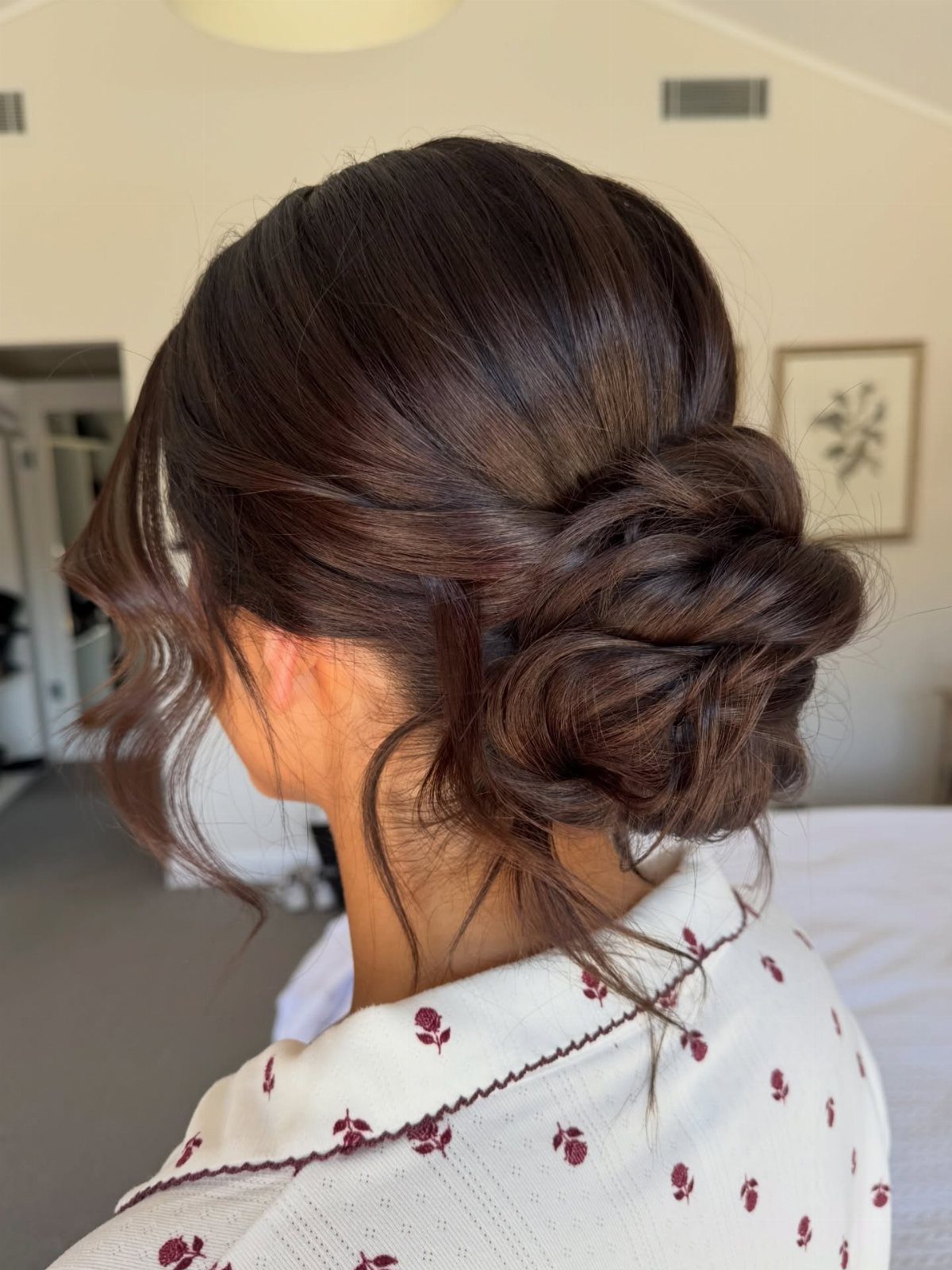 Textured low bun with twisted sections and loose tendrils on a woman
