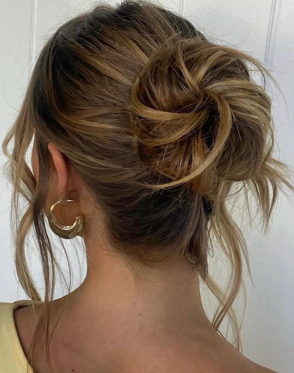 Loose brown updo with pinned twists and wispy strands, viewed from behind