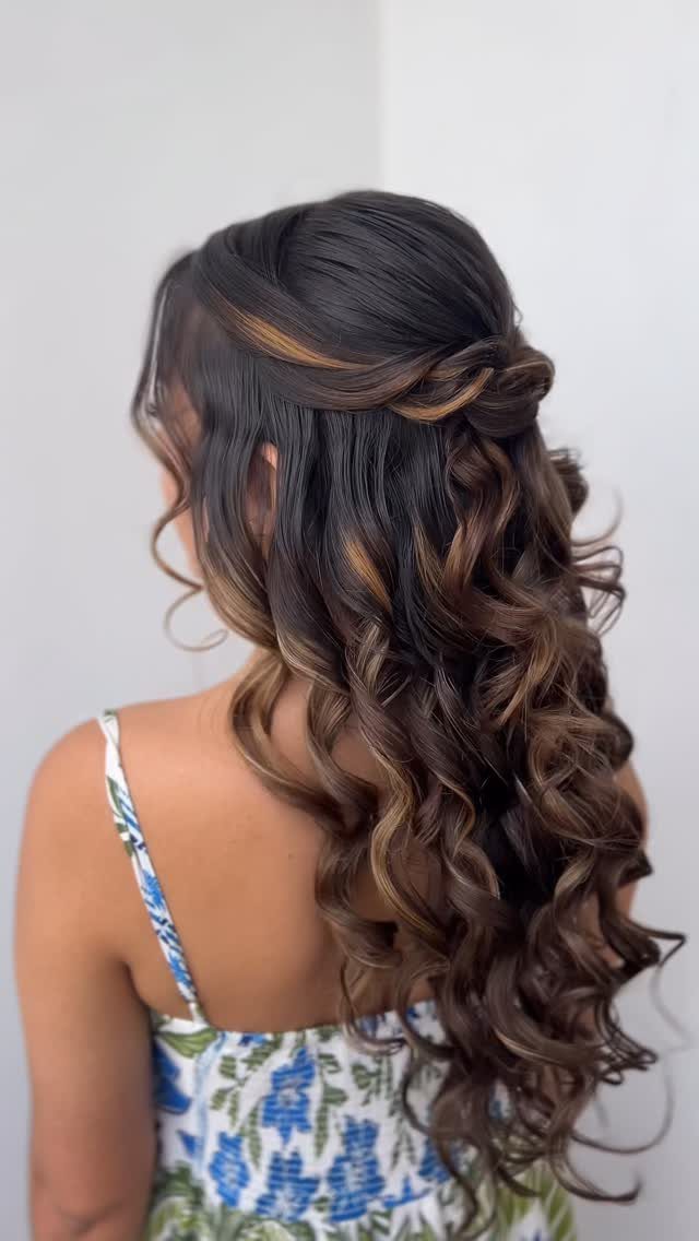 Long dark curls styled in a twisted half-up look with pinned-back sections